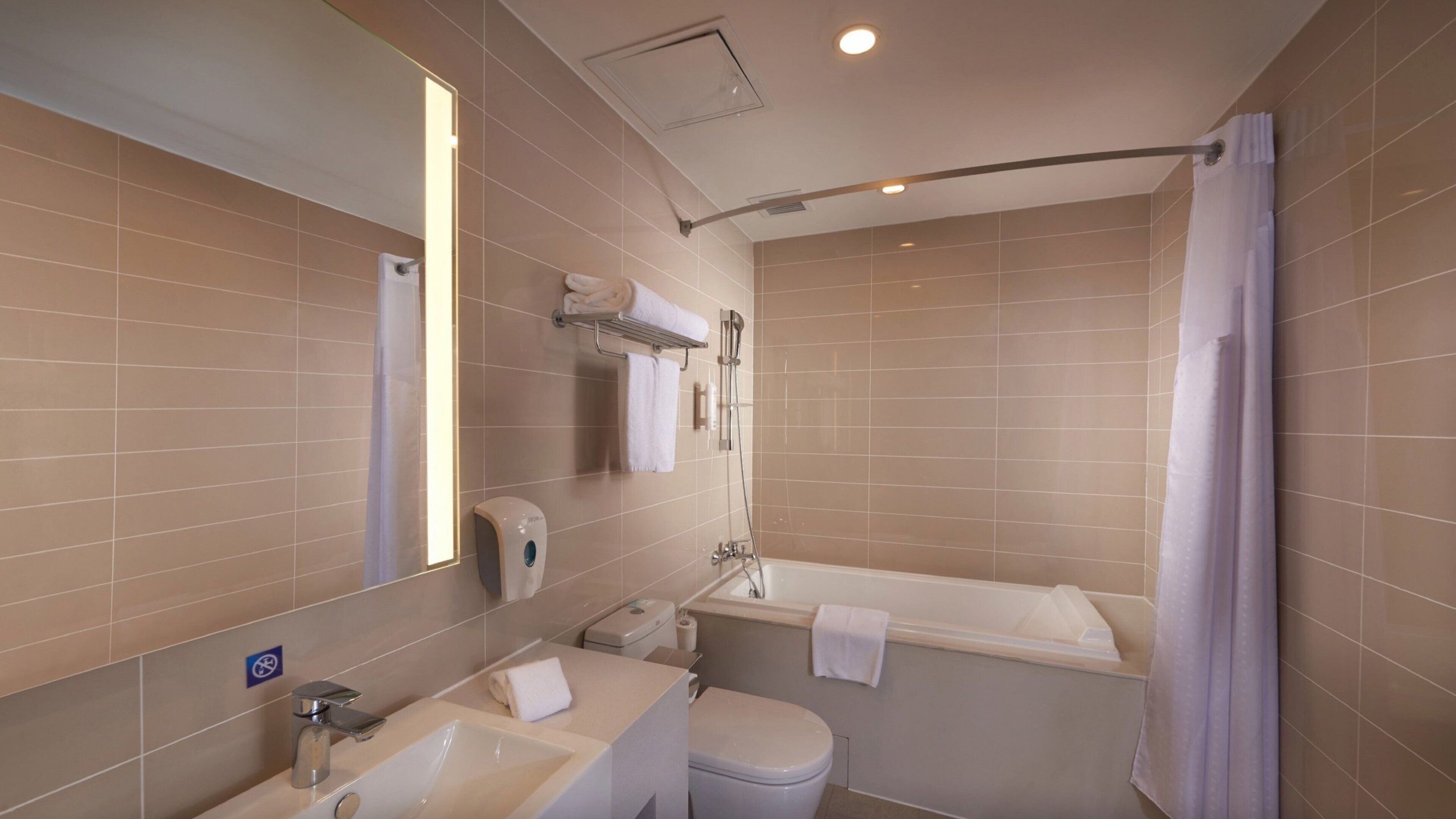 Un baño moderno con bañera, inodoro, lavabo y secamanos.