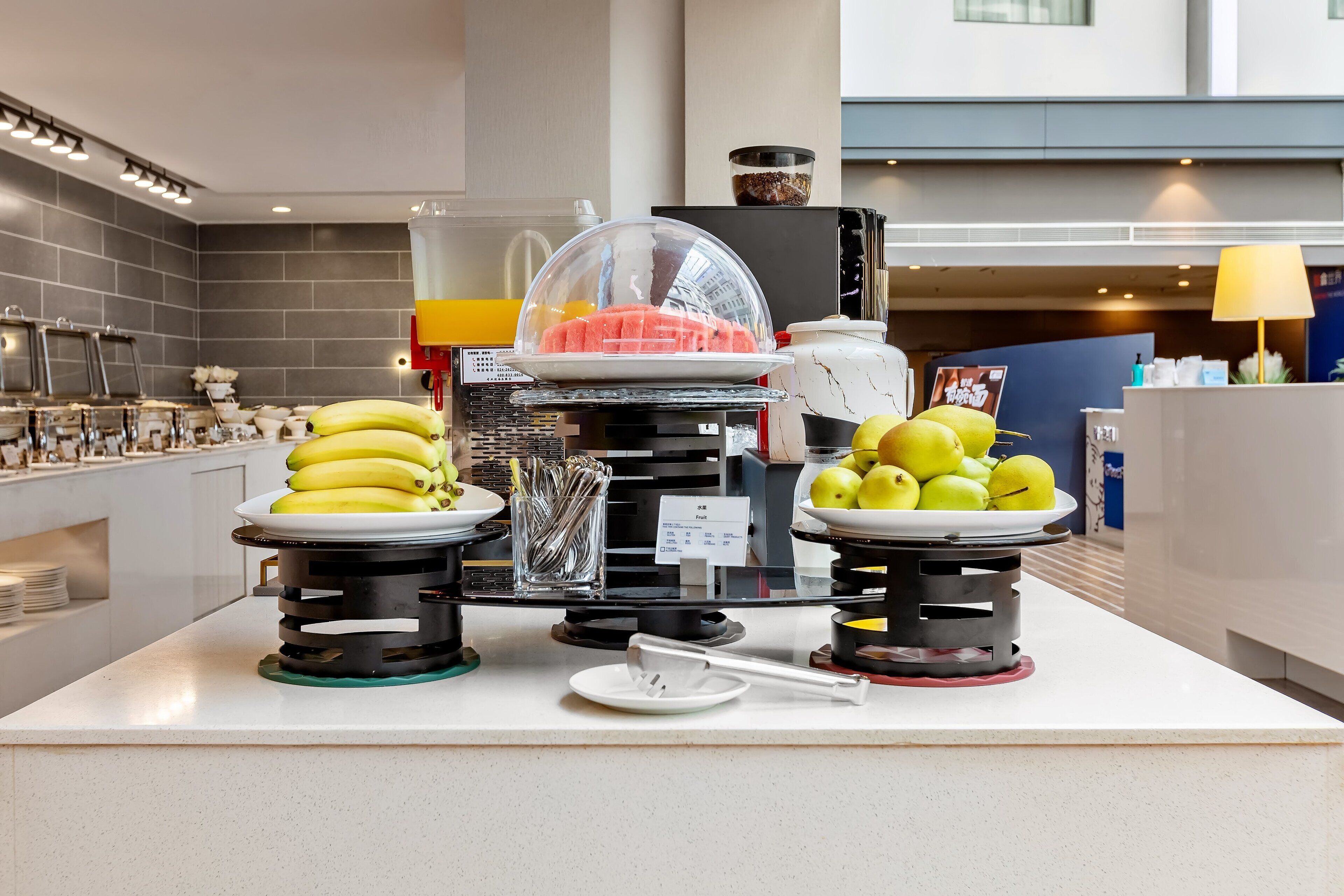 A buffet setup with bananas, apples, and a watermelon on display.
