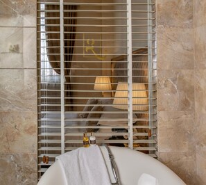 A bathroom with a bathtub, a towel, and toiletries on a shelf.