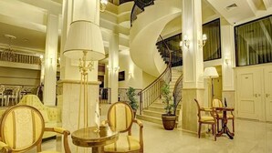 Un hall imponente con suelo de mármol, una escalera de caracol y muebles clásicos.