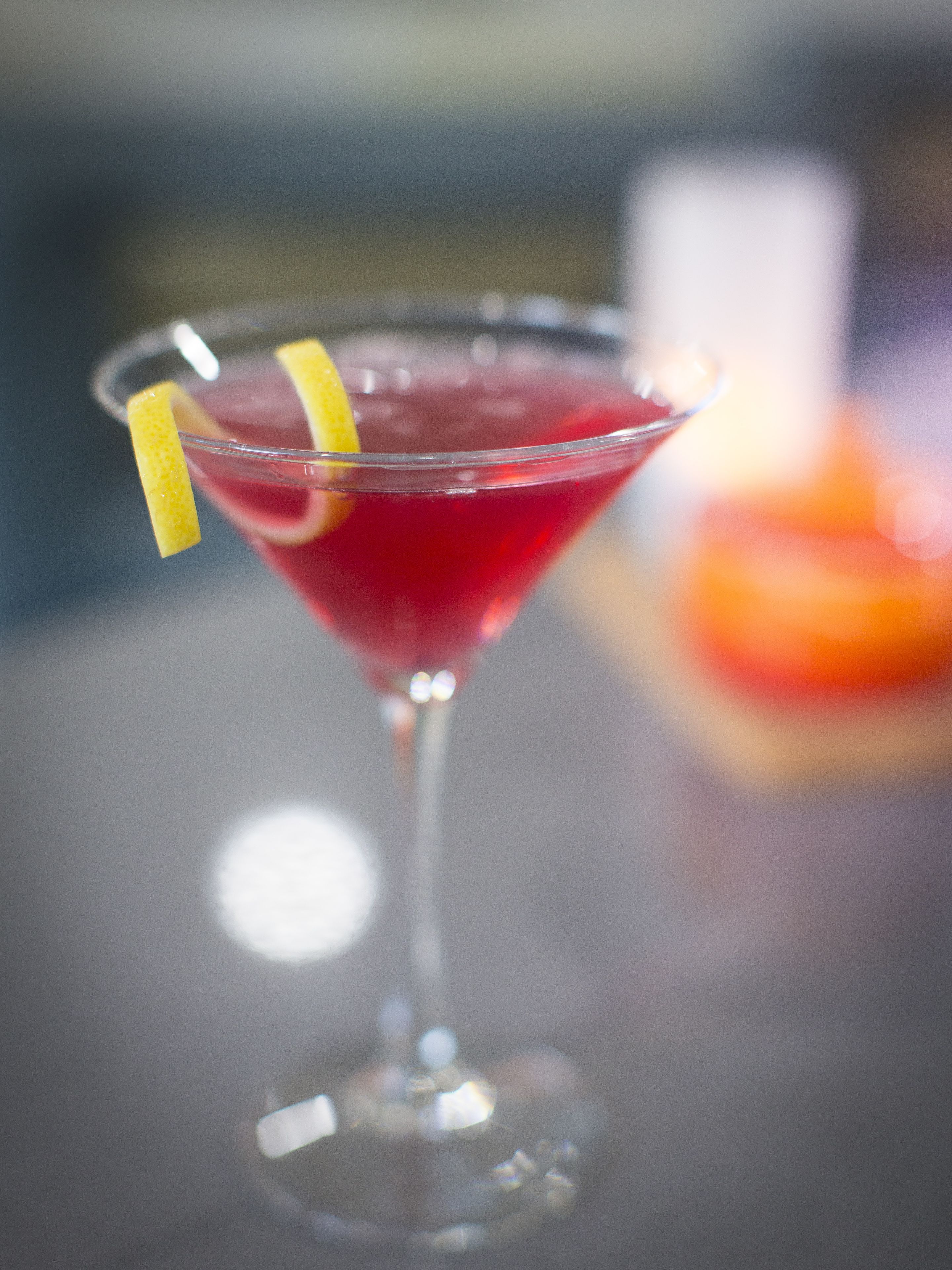 A cocktail in a martini glass with a lemon garnish.