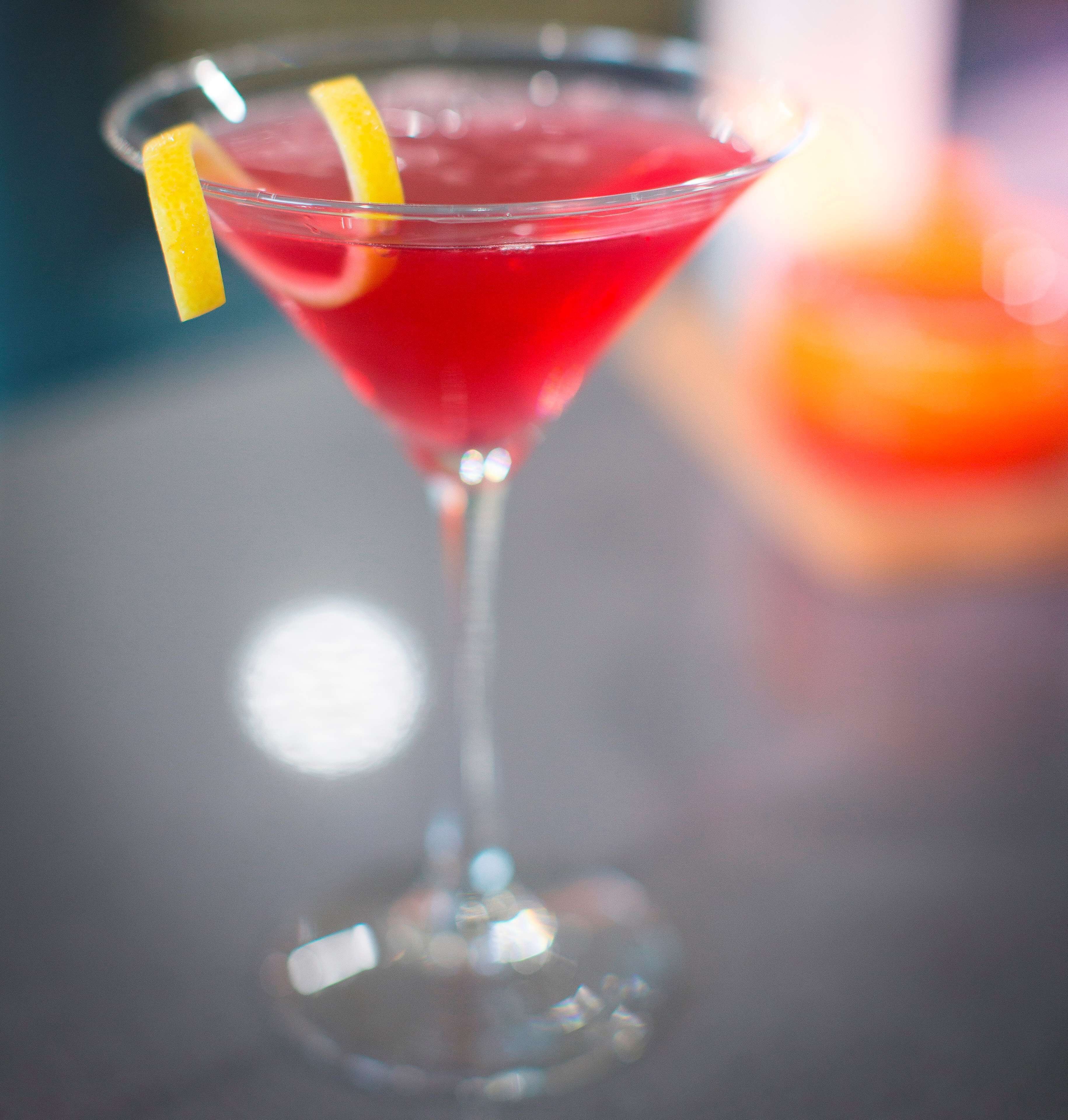A cocktail in a martini glass with a lemon garnish.