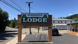 A sign for Evergreen Lodge with a parking lot and a building in the background. - Evergreen Lodge (Mount Shasta)