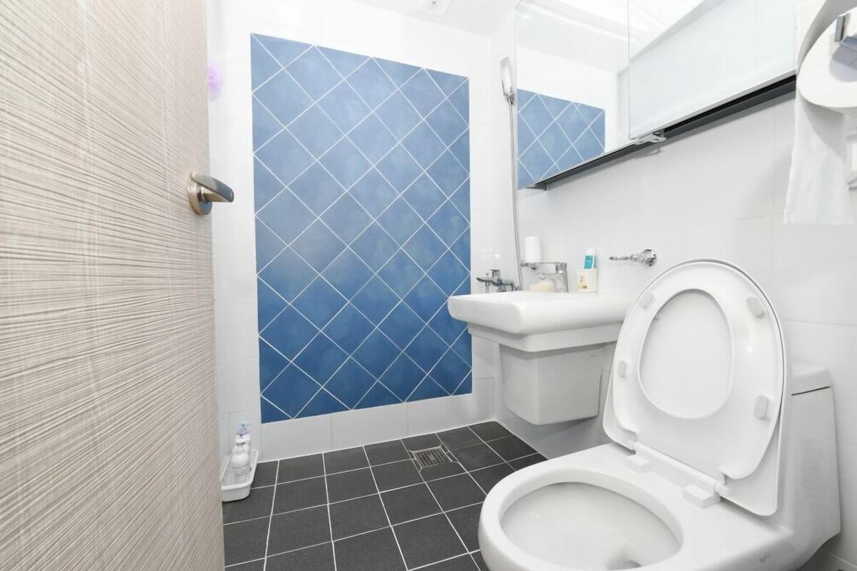 A modern bathroom with a white toilet, a sink, and a shower area with blue tiles.