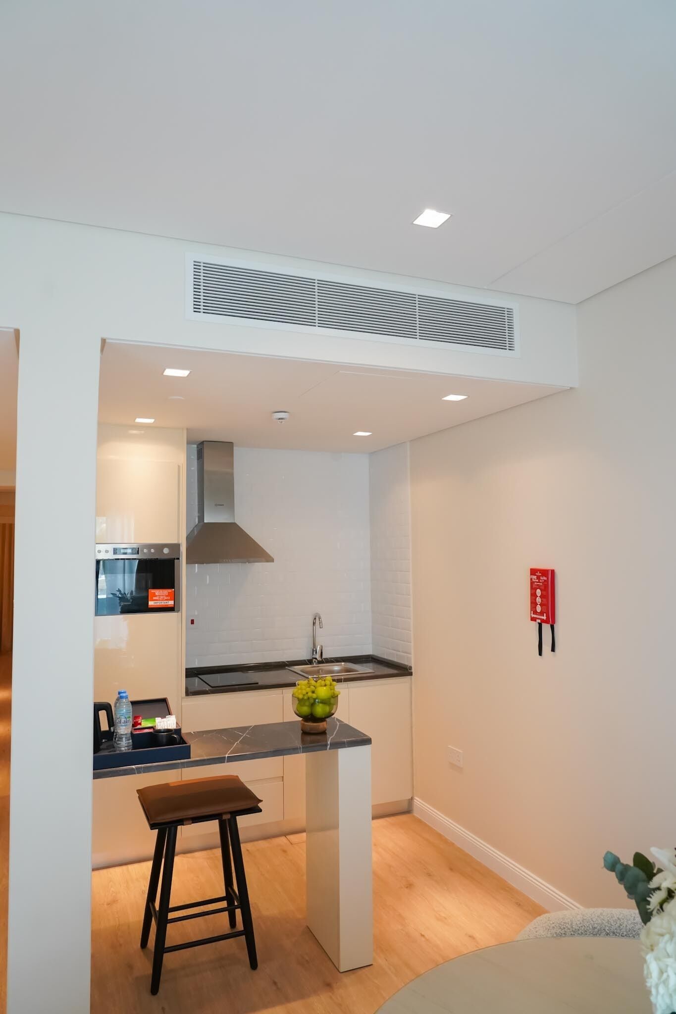 A modern kitchen with white cabinetry, a black countertop, and a stainless steel range hood.