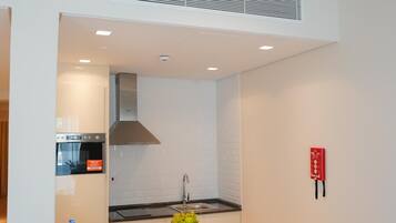 A modern kitchen with white cabinetry, a black countertop, and a stainless steel range hood.