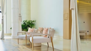 A modern hotel lobby with a sofa set, a potted plant, and a large window with curtains. - Andalus Al Seef Resort & Spa (Abu Dhabi)