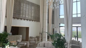 A spacious lobby with a high ceiling, large windows, and a modern chandelier. There are multiple seating areas with sofas and a coffee table. - Andalus Al Seef Resort & Spa (Abu Dhabi)
