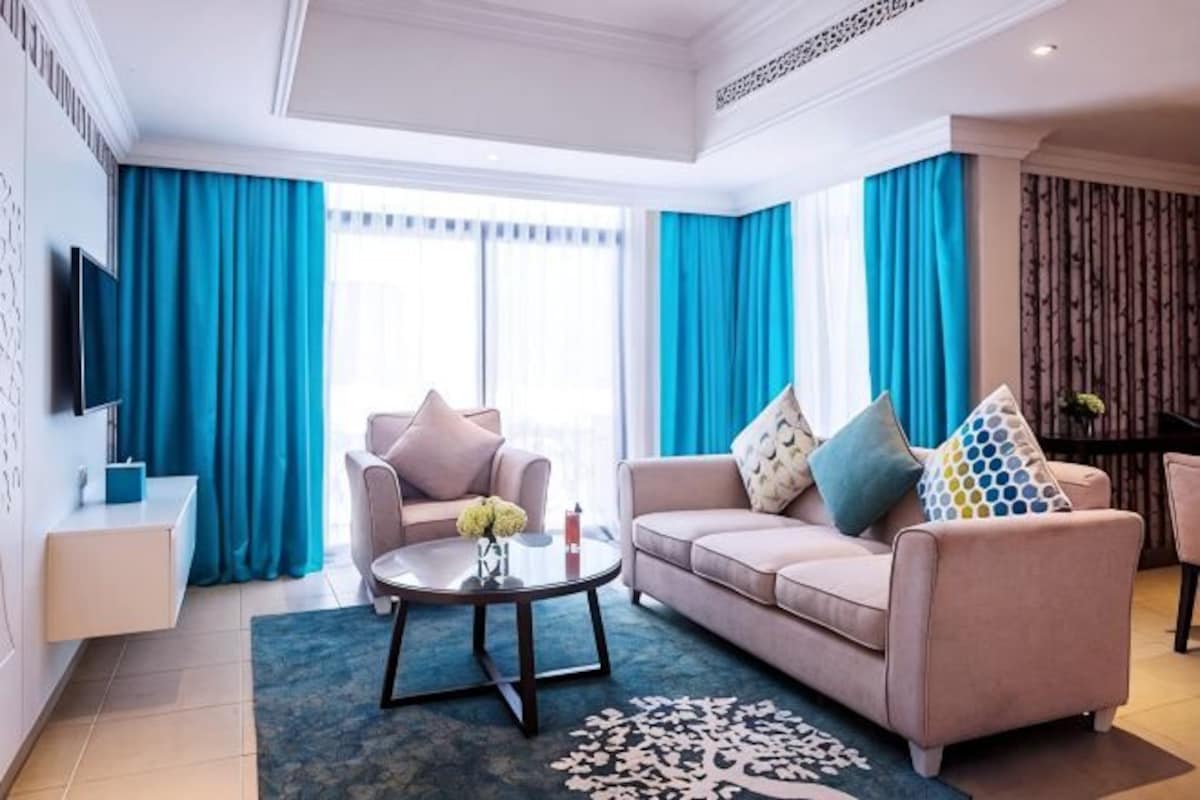 A living room with a sofa, armchairs, a coffee table, and a TV.