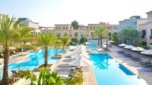 A resort with multiple swimming pools, palm trees, and lounge areas. - Andalus Al Seef Resort & Spa (Abu Dhabi)