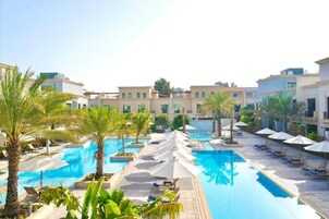 Una piscina al aire libre, sombrillas, sillones reclinables de piscina