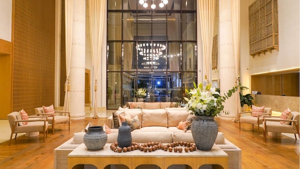 A spacious lobby with a large beige sofa, two side tables with vases, and a wooden reception desk. - Andalus Al Seef Resort & Spa (Abu Dhabi)