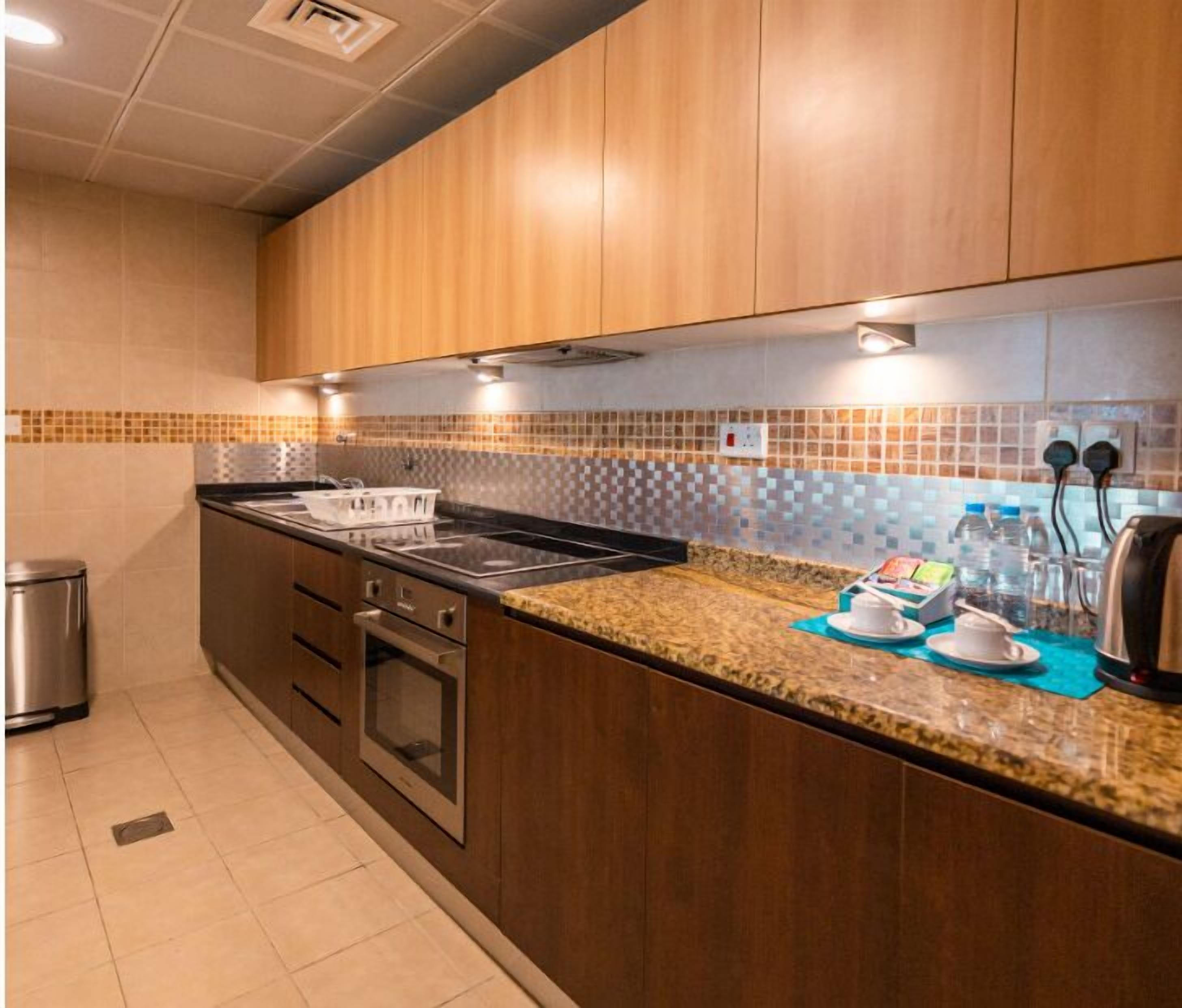 A modern kitchen with wooden cabinets, a granite countertop, and a built-in oven.