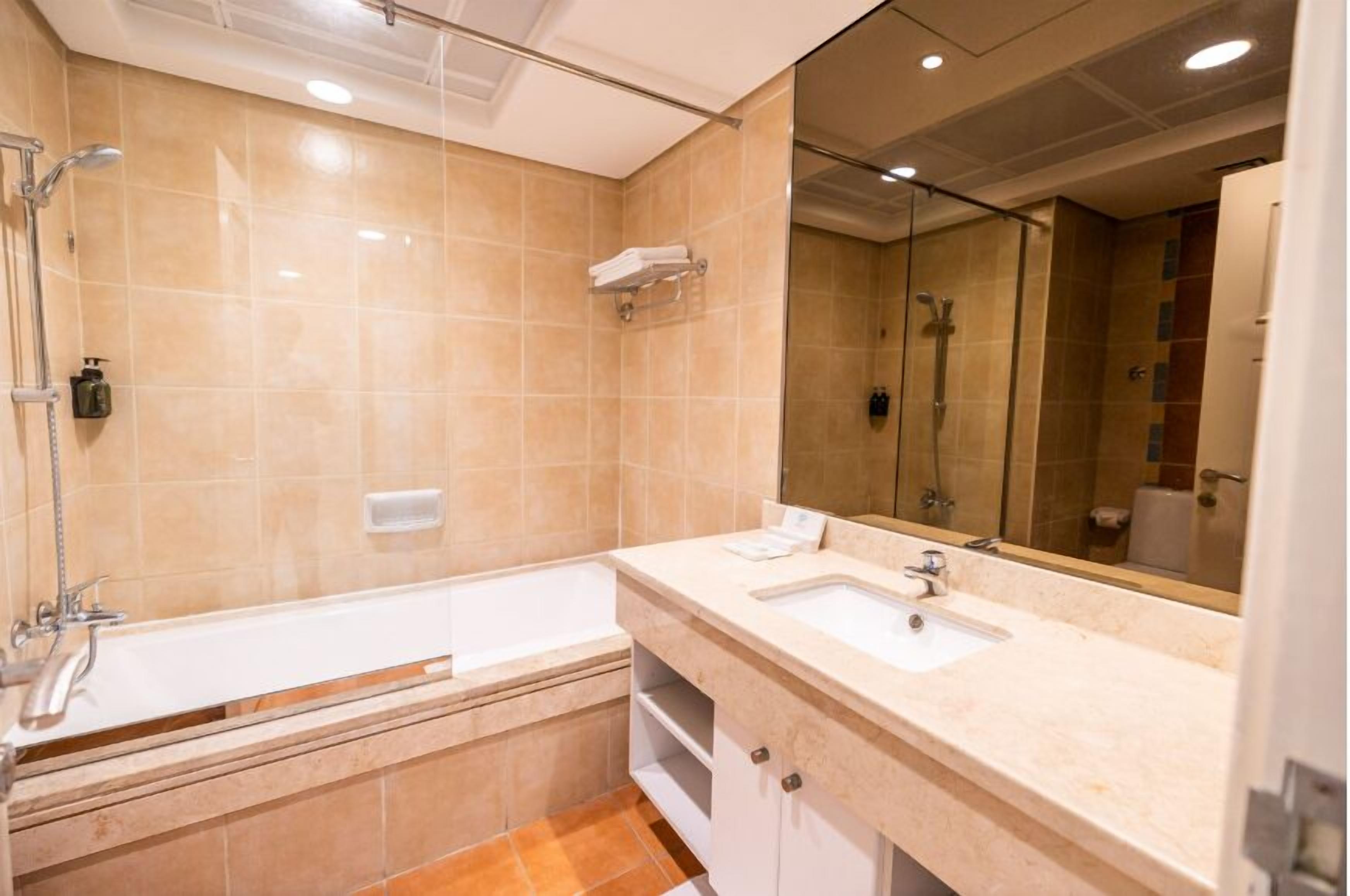 Un baño moderno con bañera, dos lavabos, un espejo grande y zona de ducha.