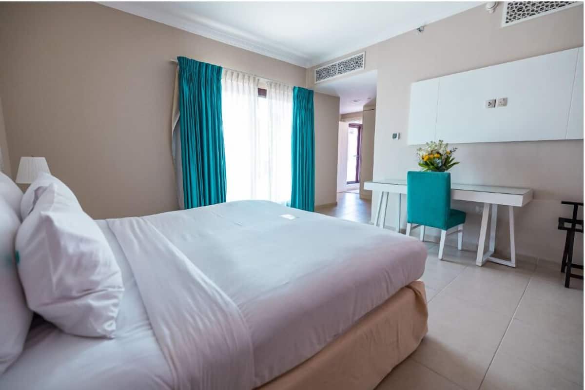 A hotel room with a large bed, a desk, and a chair.