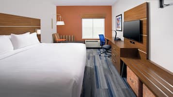 A hotel room with a large bed, a desk with a flat-screen TV, a chair, and a window with blinds.