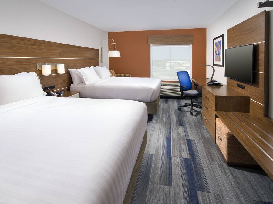 A hotel room with two beds, a desk, a chair, a TV, and a window with a view.