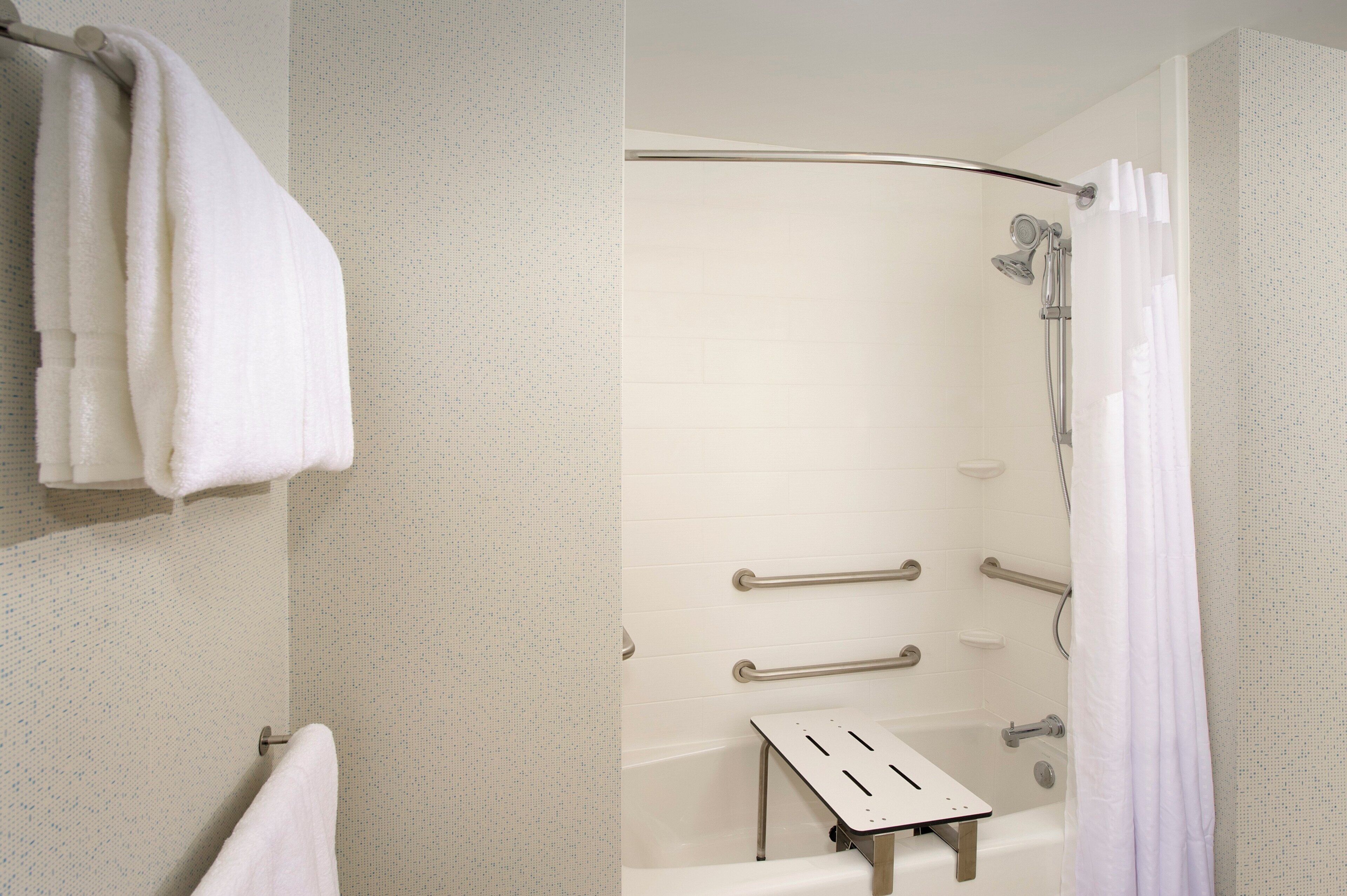 Une salle de bain équipée d’une douche, de barres d’appui et d’un porte-serviettes.