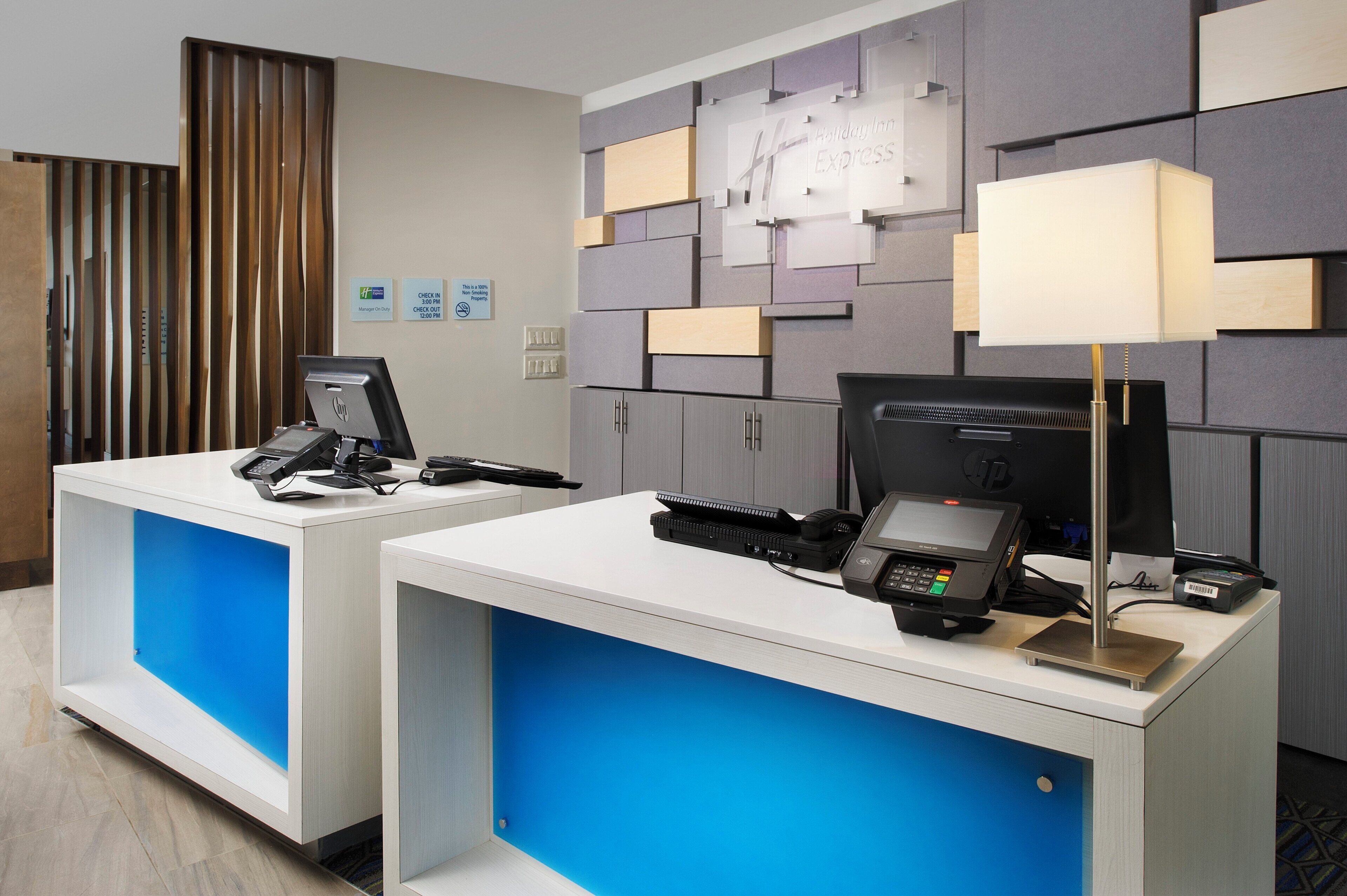 A hotel reception desk with a check-in counter, a computer, a telephone, and a cash register.