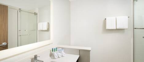 A modern bathroom with a large mirror, a sink, and a shower area.