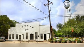 A white building with "GRUENE Hall" written on the side, surrounded by potted plants and a water tower in the background. - Holiday Inn Express & Suites New Braunfels by IHG (New Braunfels)