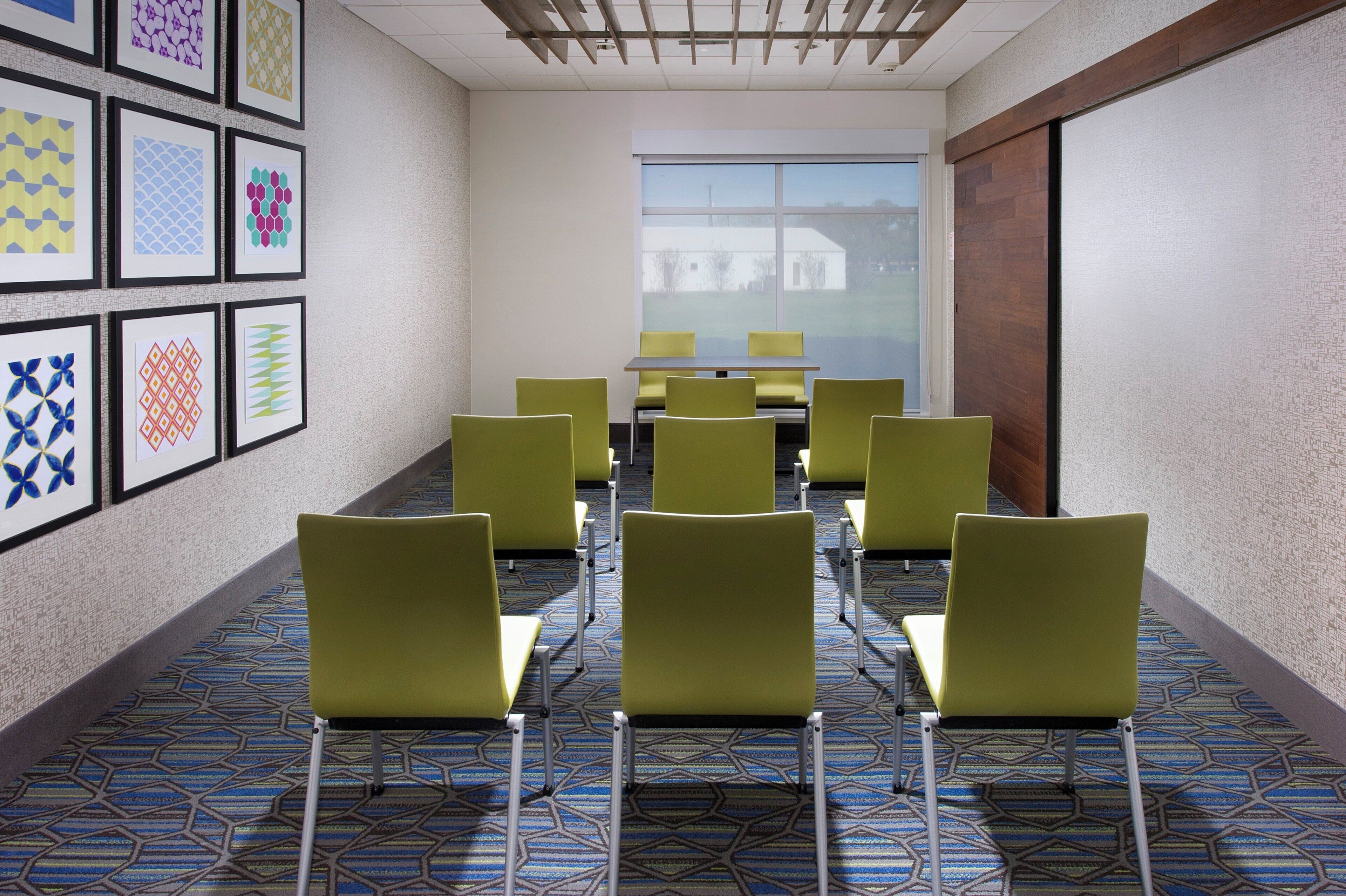 A conference room with a long table and chairs, a patterned carpet, and framed artwork on the walls.