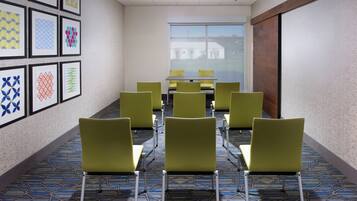 A conference room with a long table and chairs, a patterned carpet, and framed artwork on the walls.
