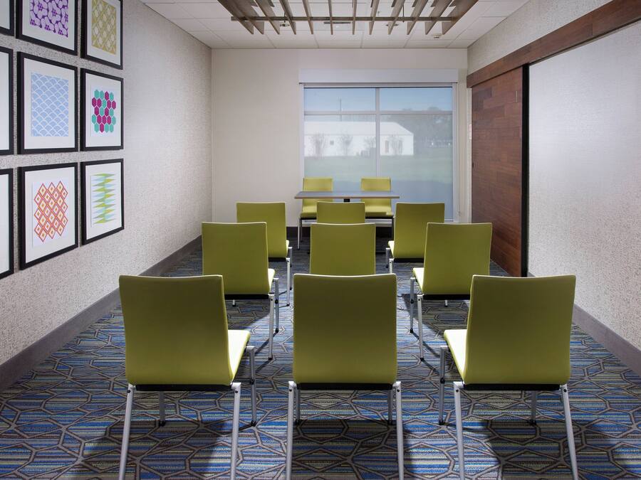 A conference room with a long table and chairs, a patterned carpet, and framed artwork on the walls.