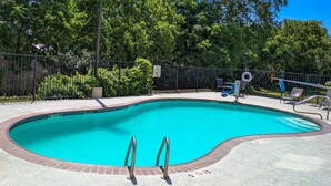 A swimming pool with a brick edge, metal handrails, and a fenced area with lounge chairs. - Holiday Inn Express & Suites New Braunfels by IHG (New Braunfels)