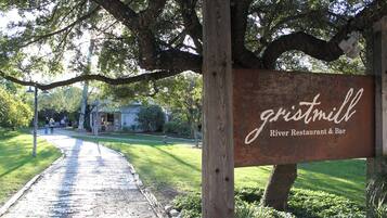 A rustic wooden sign for a restaurant and bar named 'gristmill' with a paved pathway leading to it.