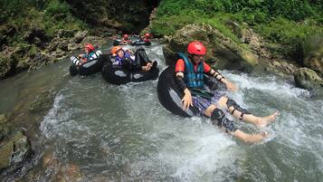 Personas hacen rafting en un río rodeado de rocas y vegetación.