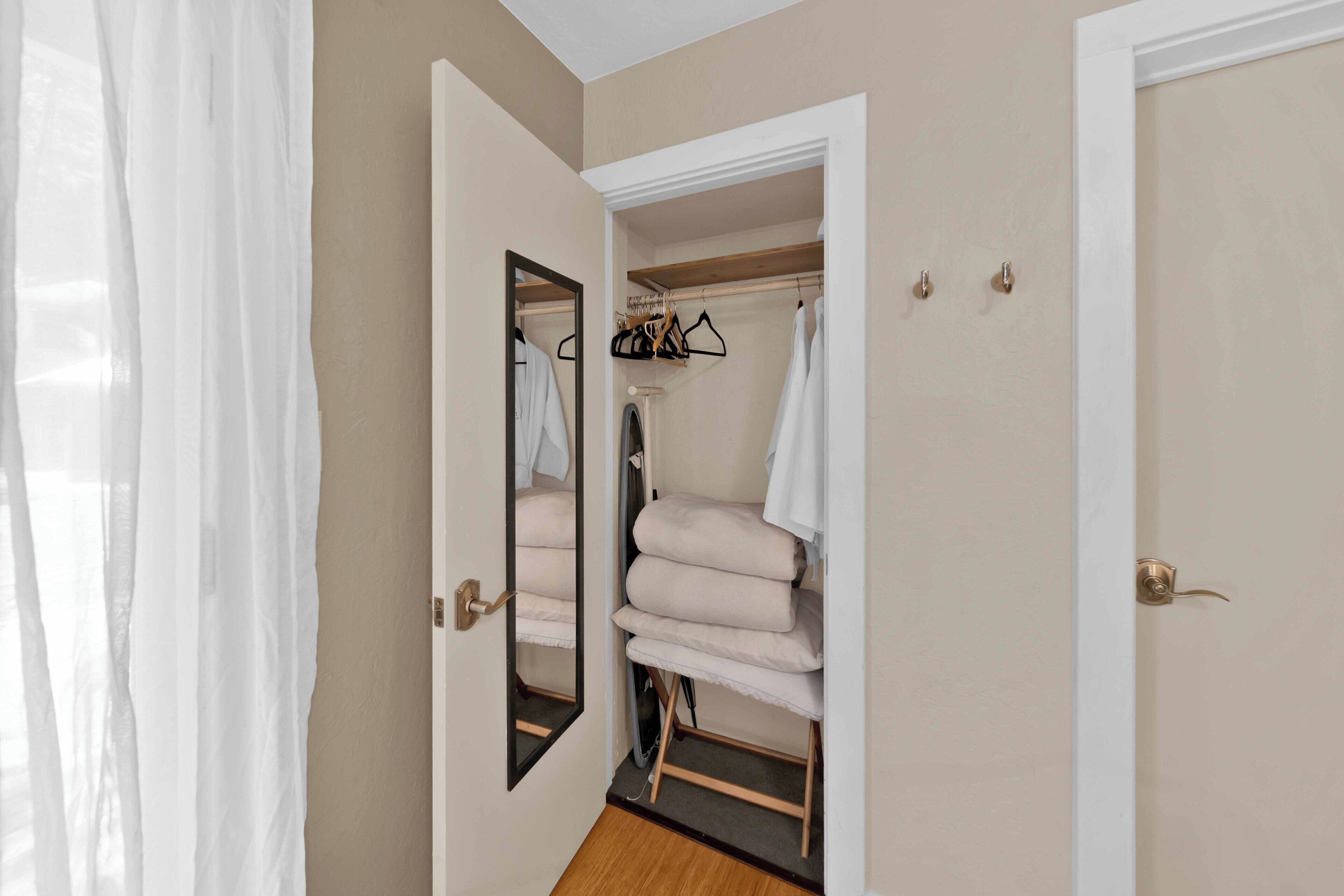 A walk-in closet with hanging space and shelves, a mirror, and a door with a handle.