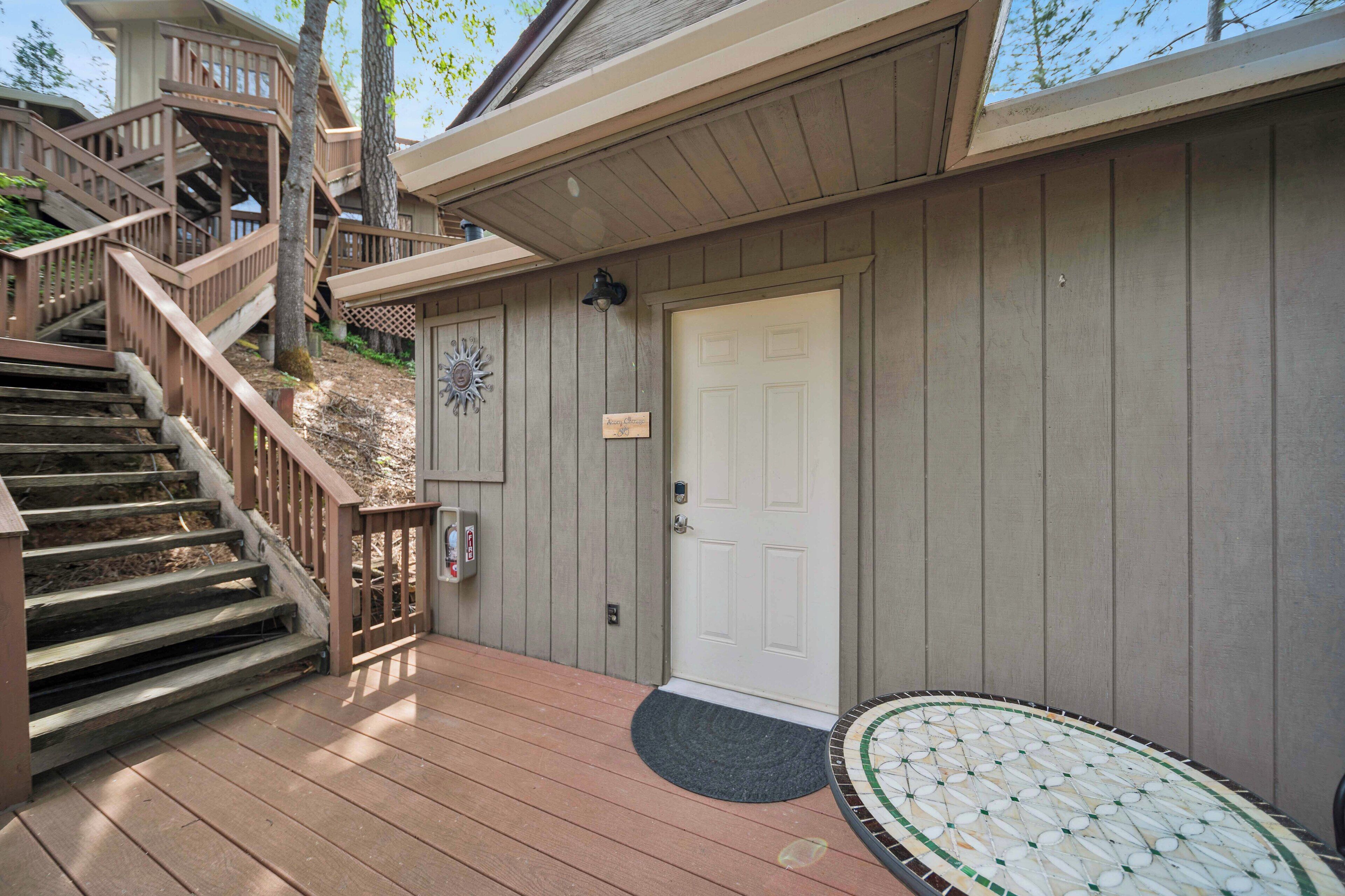 A wooden deck with a staircase leading to a covered area, a white door, and a small outdoor seating area.