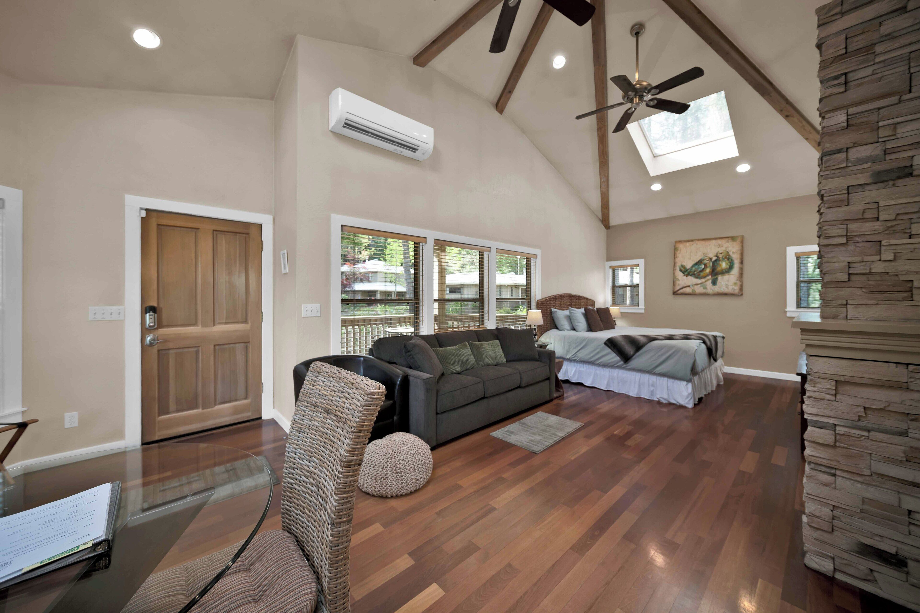 A spacious living area with a high ceiling, a ceiling fan, and a large window providing natural light.