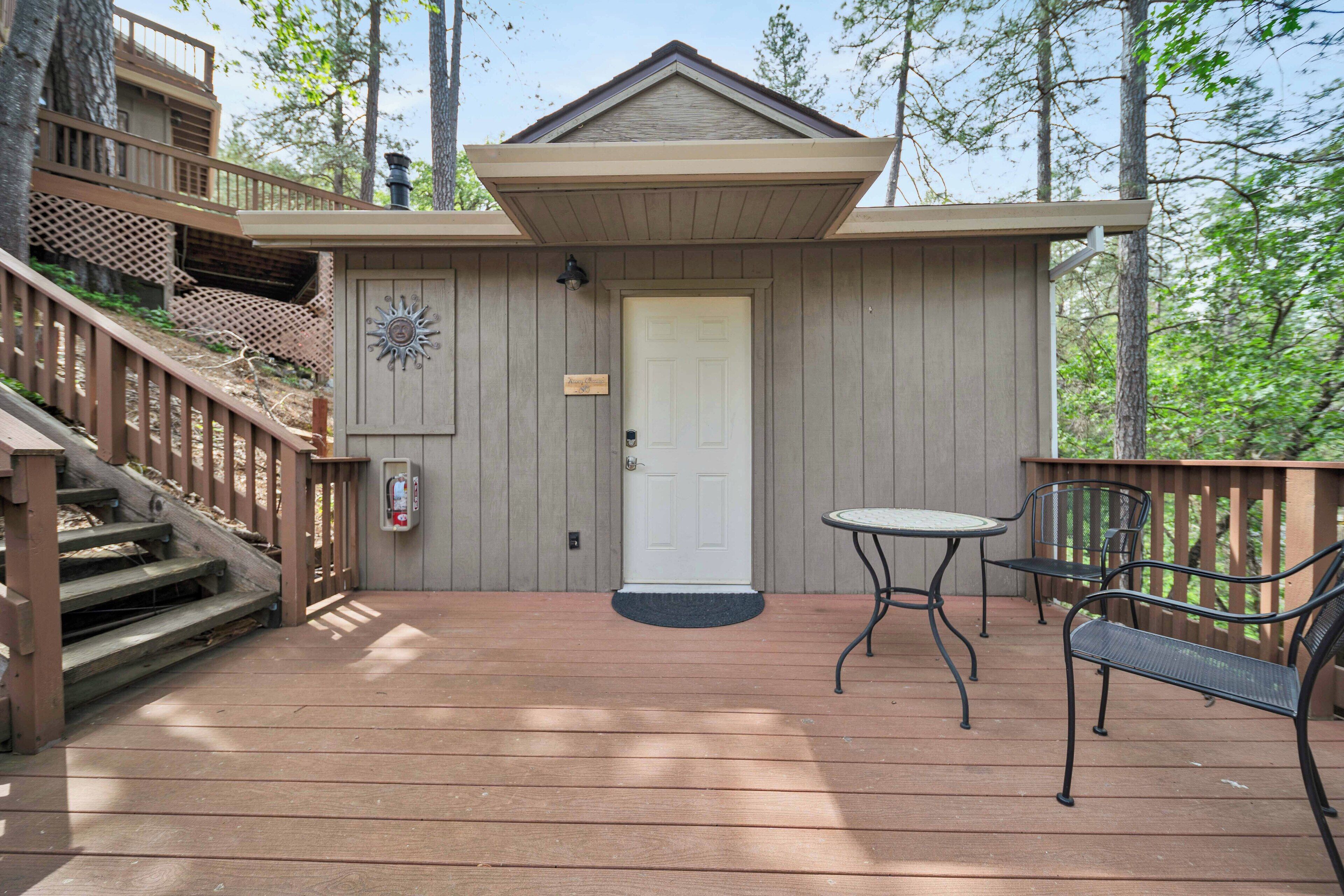 A wooden deck with a white door, a small table, and two chairs.