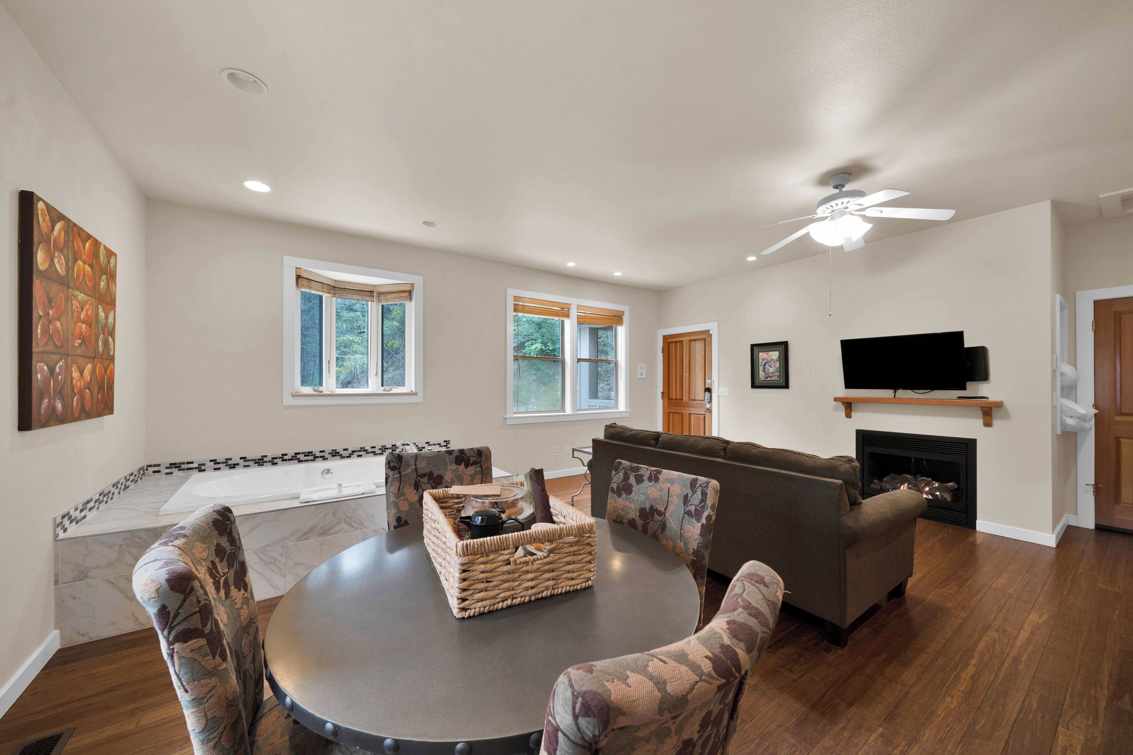 A spacious living room with a fireplace, a ceiling fan, and a television mounted on the wall.