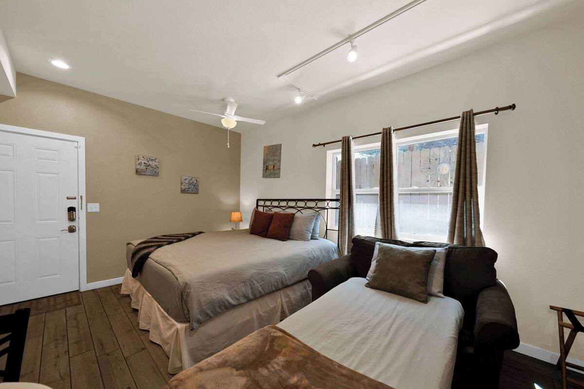 A bedroom with two beds, a ceiling fan, and a window with curtains.