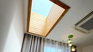 A bedroom with a skylight, a bed, curtains, and a ceiling fan. - Positano in Jeju (Seogwipo)