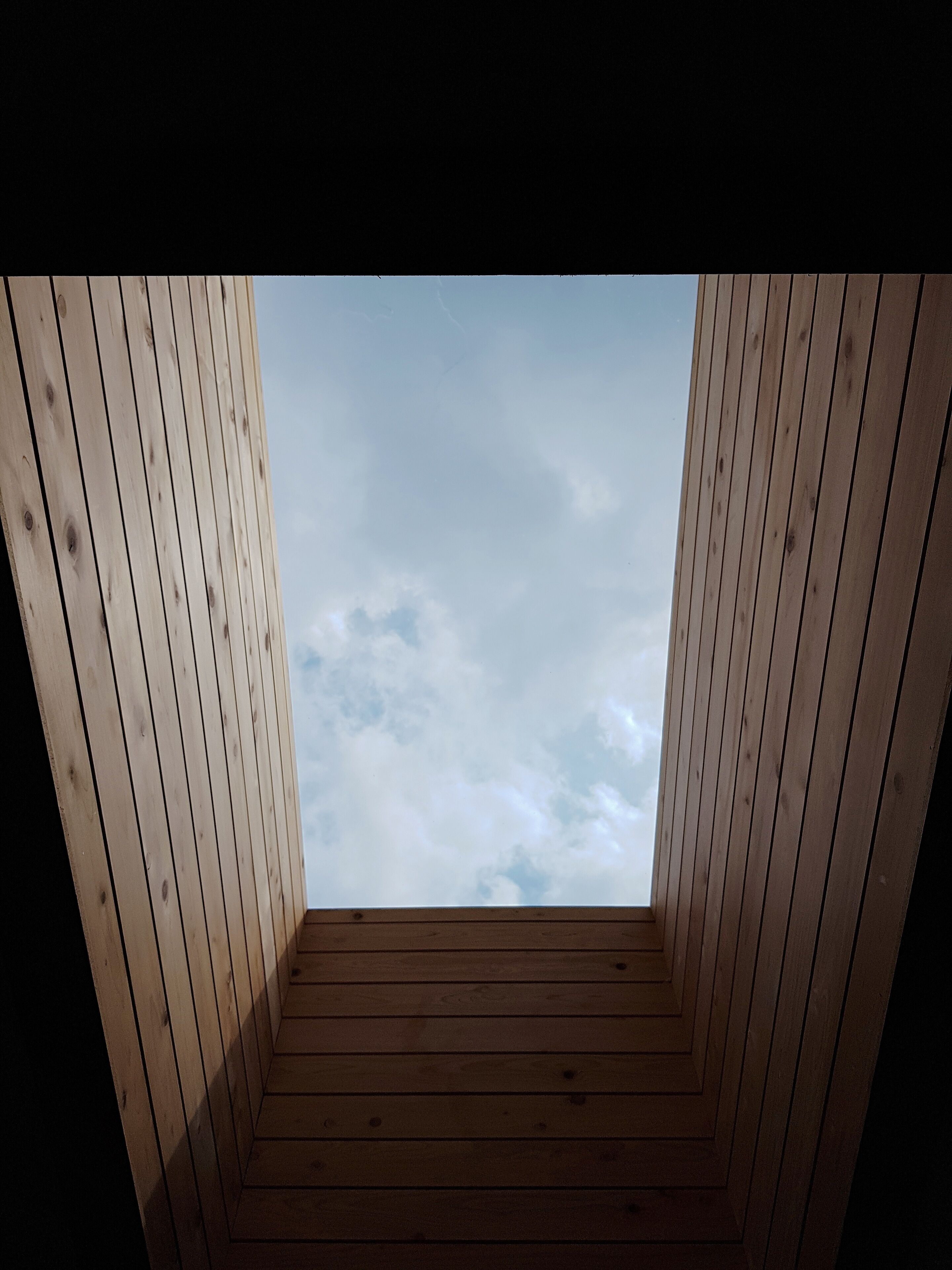 A wooden room with a view of the sky through a window.