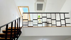 A spacious living area with a wooden staircase, a dining table, and a sofa. - Positano in Jeju (Seogwipo)