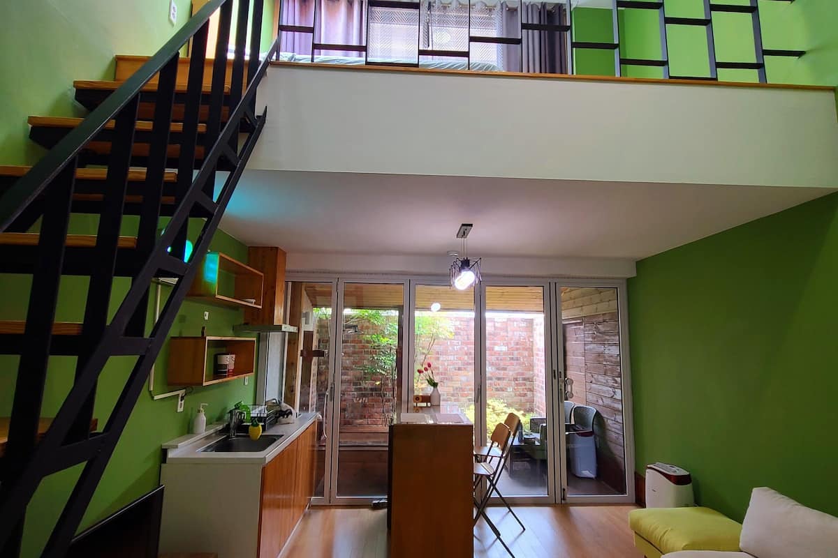A spacious living area with a staircase, a dining area, and a view of the outdoors.