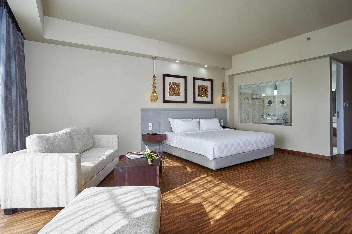 Une chambre d’hôtel moderne avec un lit, un canapé et une petite table agrémentée d’une plante.
