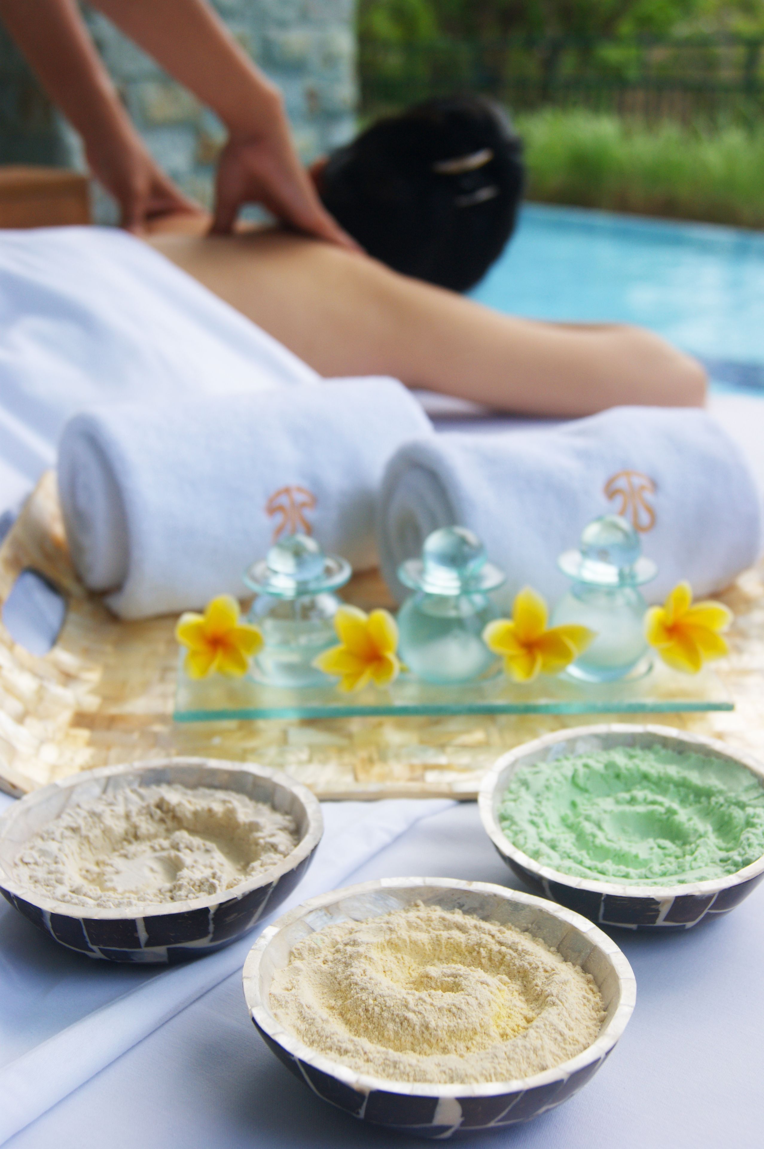 A spa setting with a massage table, towels, and bowls of bath salts.