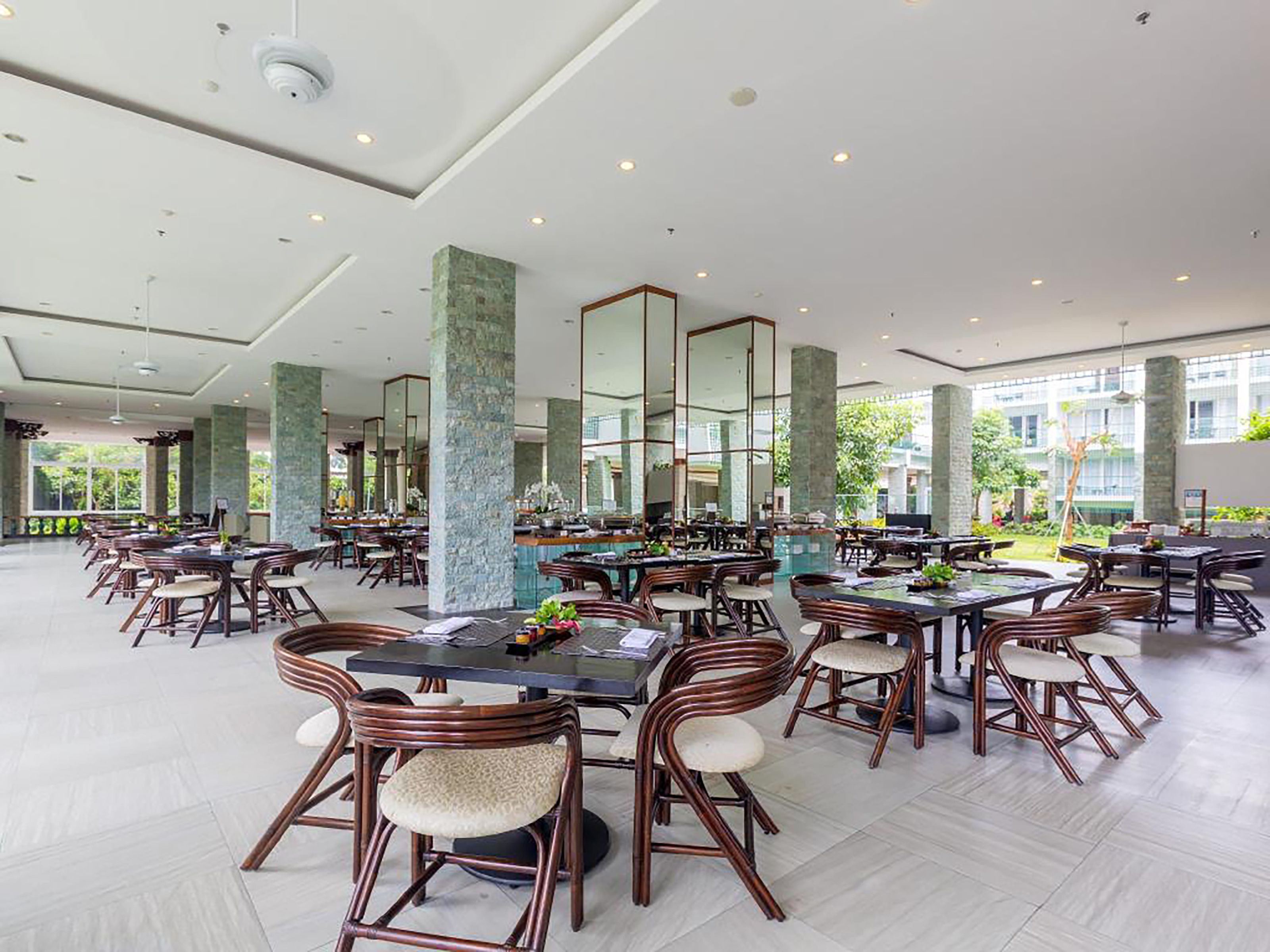 A spacious indoor dining area with multiple tables and chairs, large windows, and a modern architectural design.