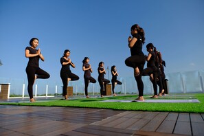A group of people performing yoga on a rooftop with a clear sky. - The Sintesa Jimbaran Bali (Jimbaran)