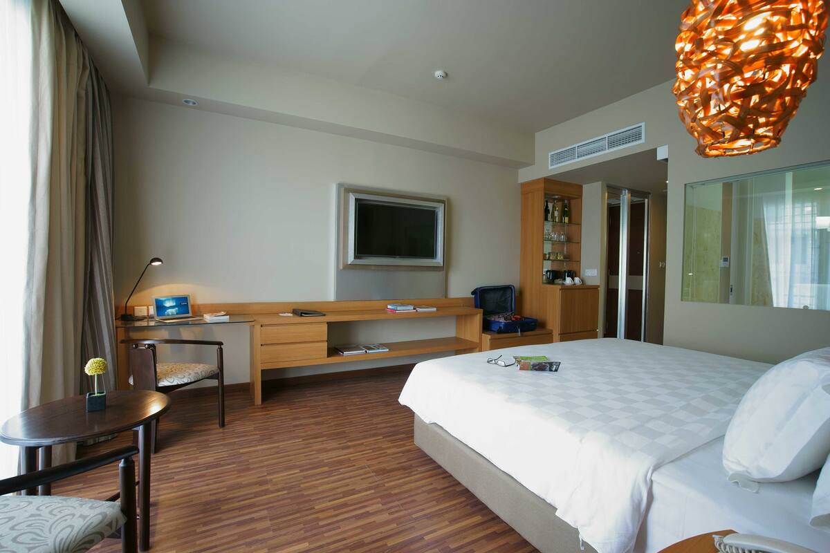 Une chambre d’hôtel comprenant un lit, un bureau avec une chaise, une télévision et une armoire.