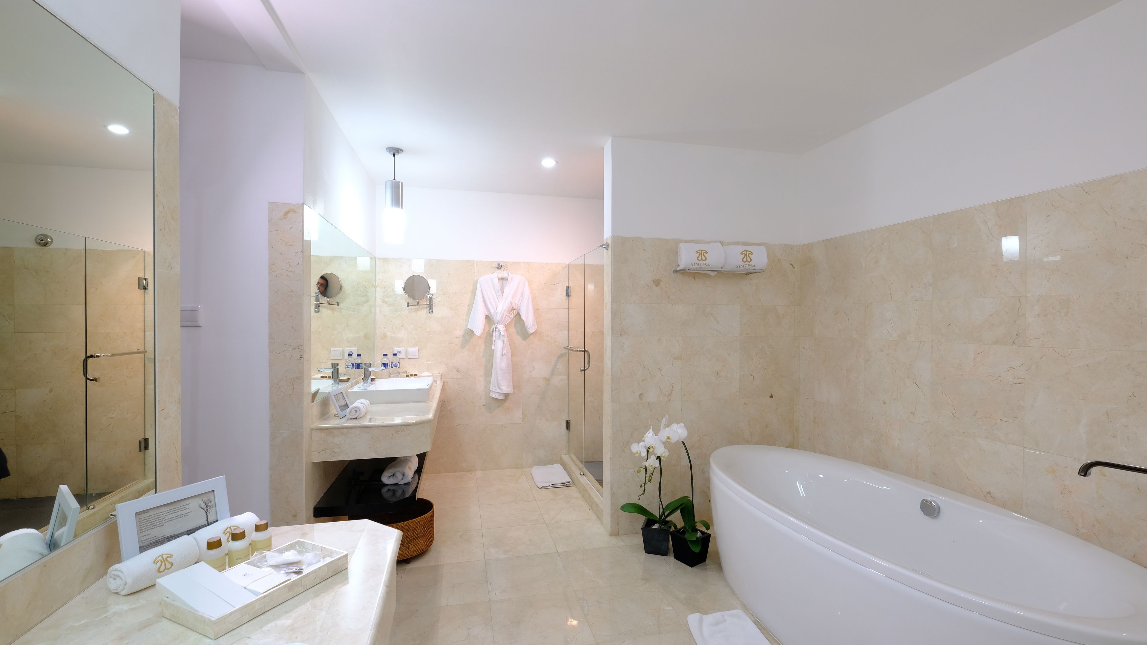 A modern bathroom with a large bathtub, a glass-enclosed shower, and a vanity with a mirror and sink.