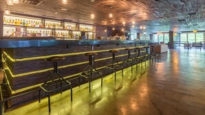 Un grand espace bar doté d’un long comptoir et de nombreux tabourets.