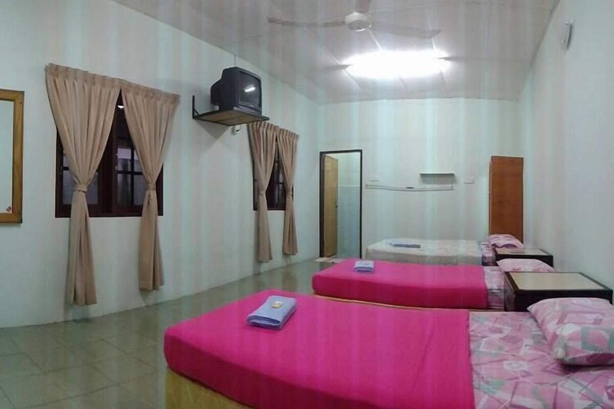 A hotel room with two beds, a television, a mirror, and a small table.