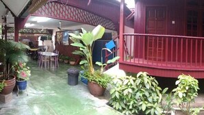 A covered outdoor area with a red railing, potted plants, and a table with chairs. - Budget Beach Resort (Pangkor Island)